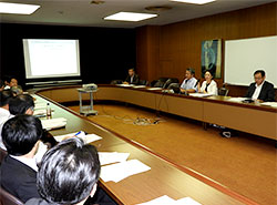 「研修10年の歩み」を画像交えて紹介する川妻委員長（右列右から２人目）